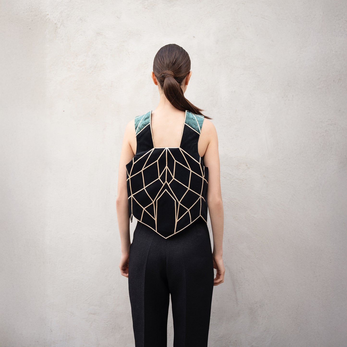 Back of the Panther Facad vest, showing the symmetrical golden geometric motif and contrasting green velvet shoulder panels.