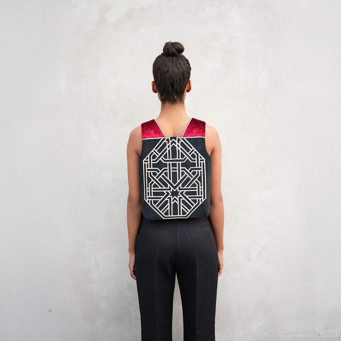 A close-up of the back of the vest, showing the detailed golden geometric motif inspired by Chehel Panjereh, framed by crimson velvet shoulder panels.