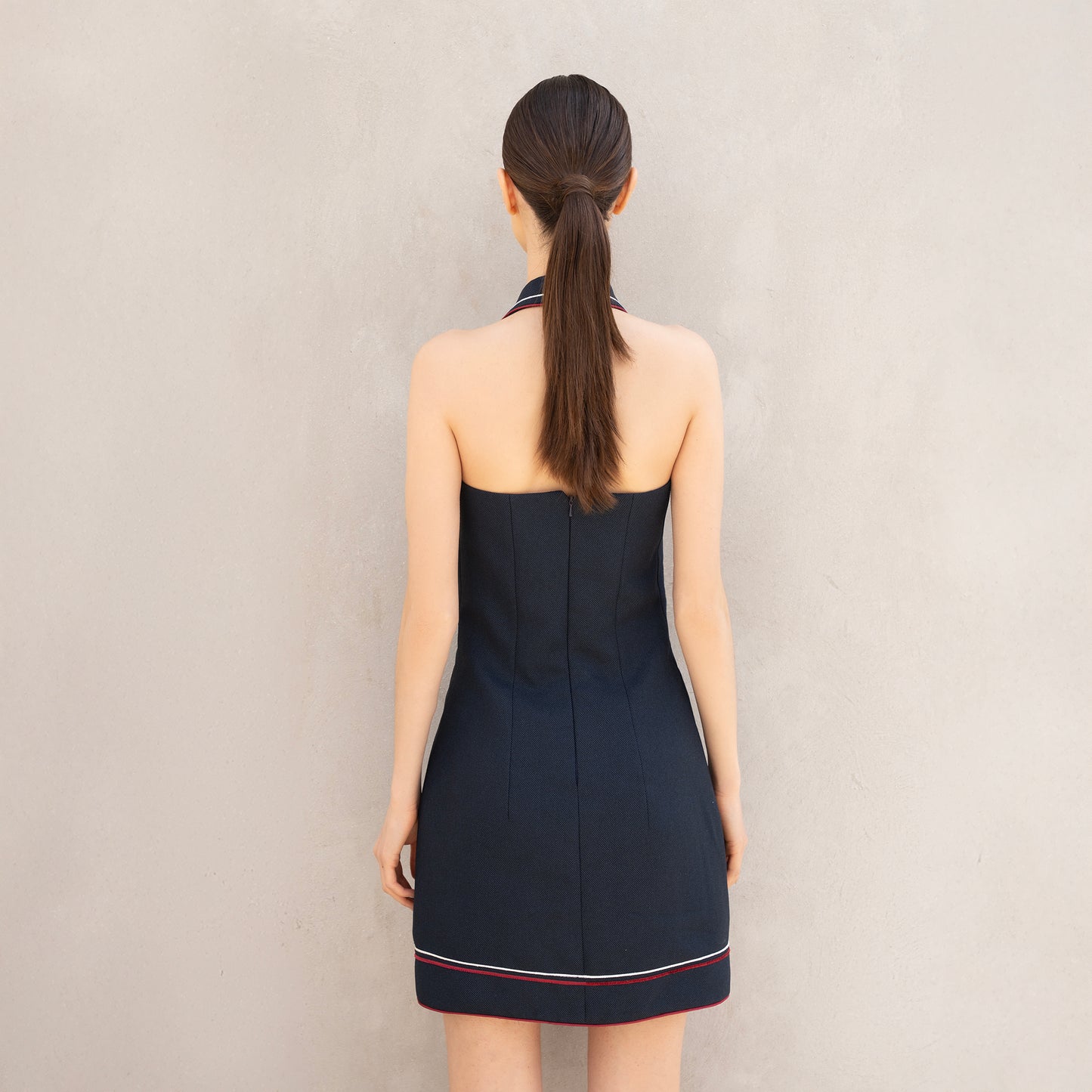 Rear view of the Pulse dress, showing the minimalist back design with subtle red and white line accents at the hem.